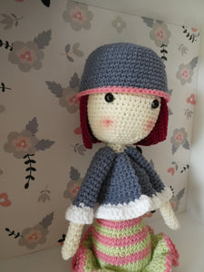 Madeline the Crochet doll in a striped dress in a display box